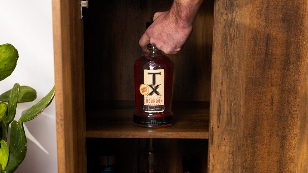 Bottle of TX Barrel Proof Bourbon in a cabinet.
