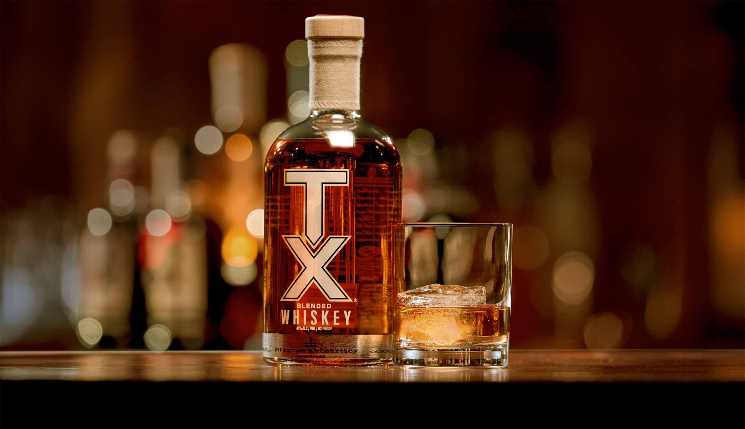 Bottle of TX Whiskey with a glass next to it